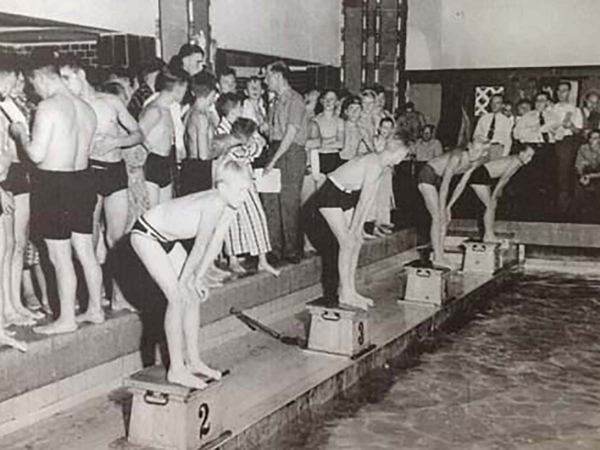 Mehrere Männer in der Männerhalle springen ins Wasser.